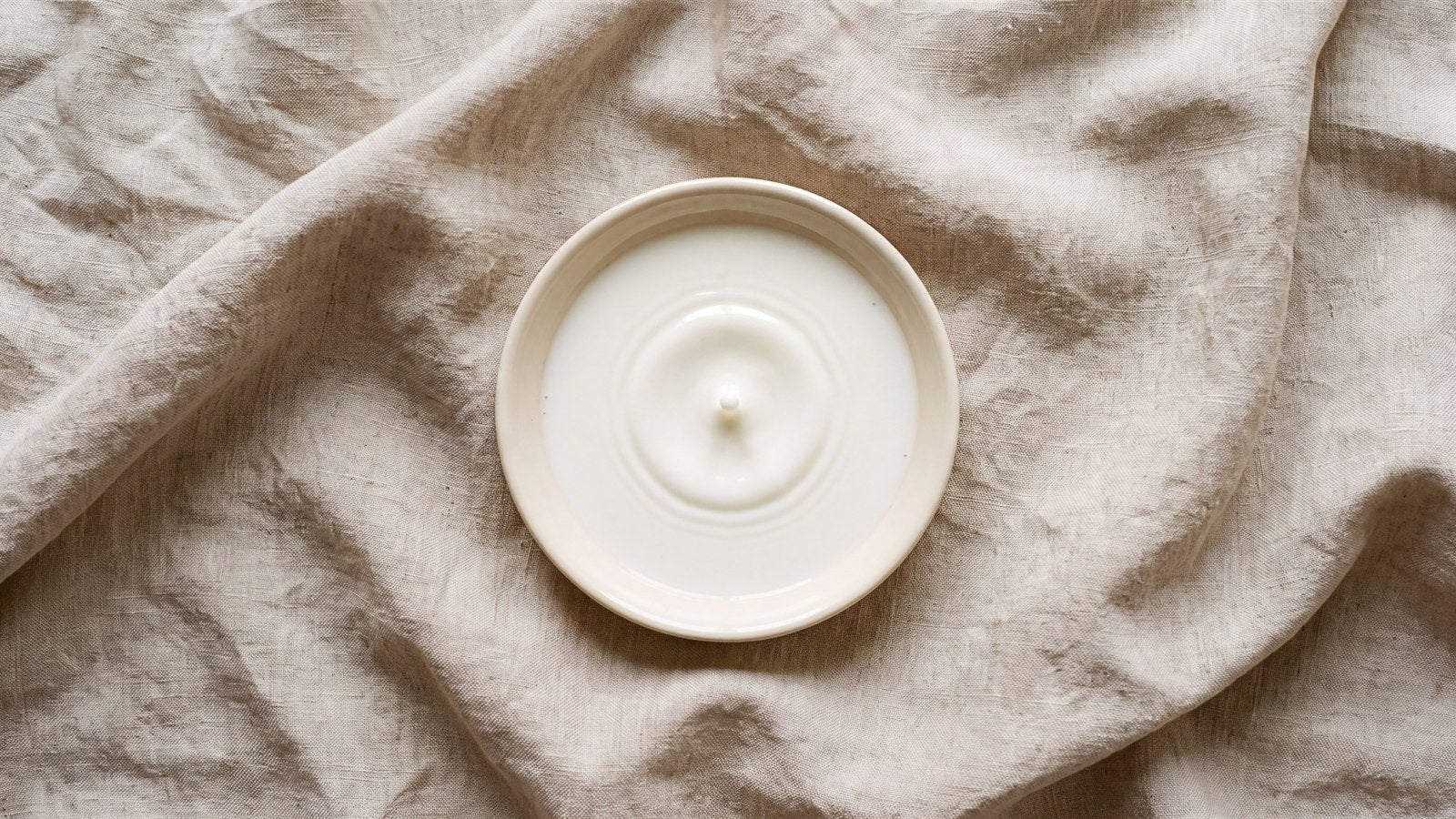 A single drop falling into a shallow ceramic dish of milk, the source lactoferrin is isolated from