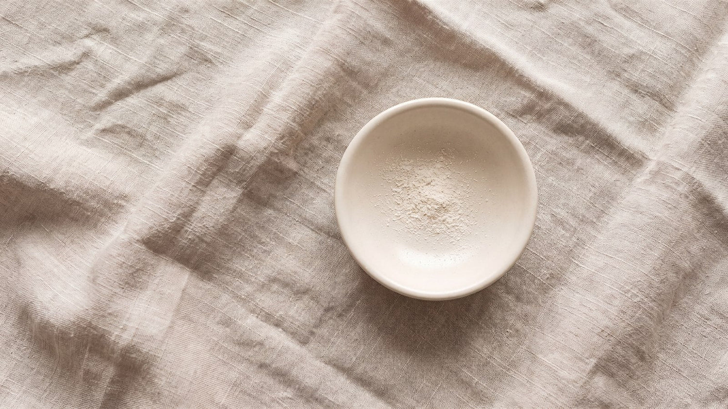 A small ceramic dish holding a very small quantity of pale powder, far more empty dish than powder